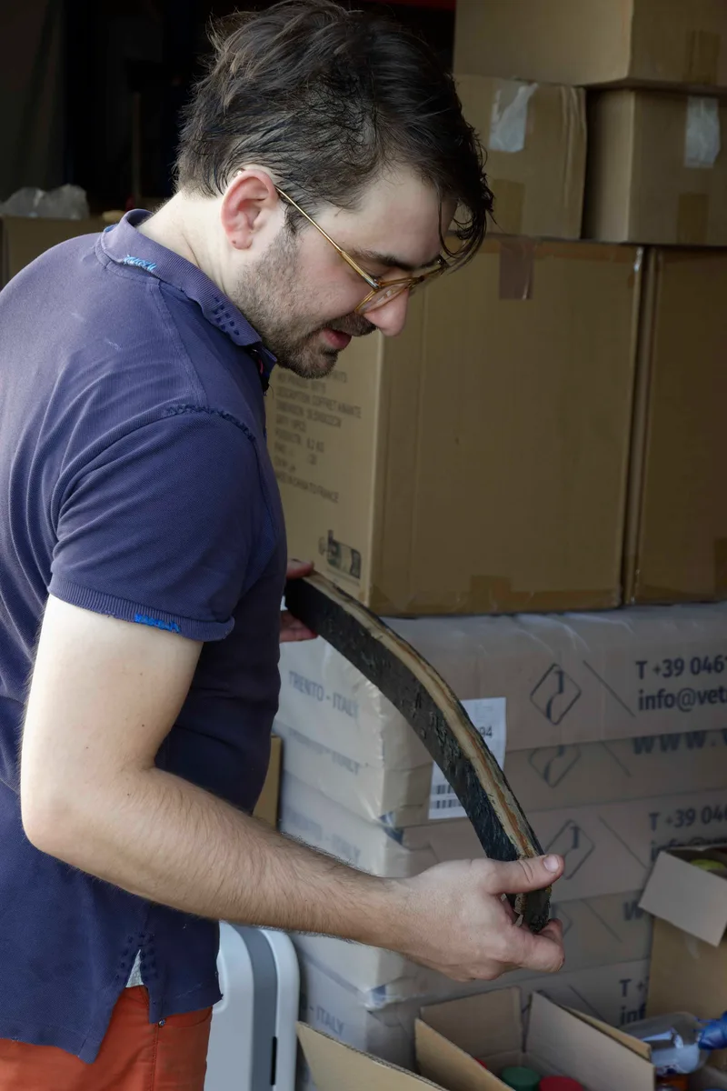 Nicolas Petit holding up a toasted cask stave and inspecting its charred inner face.