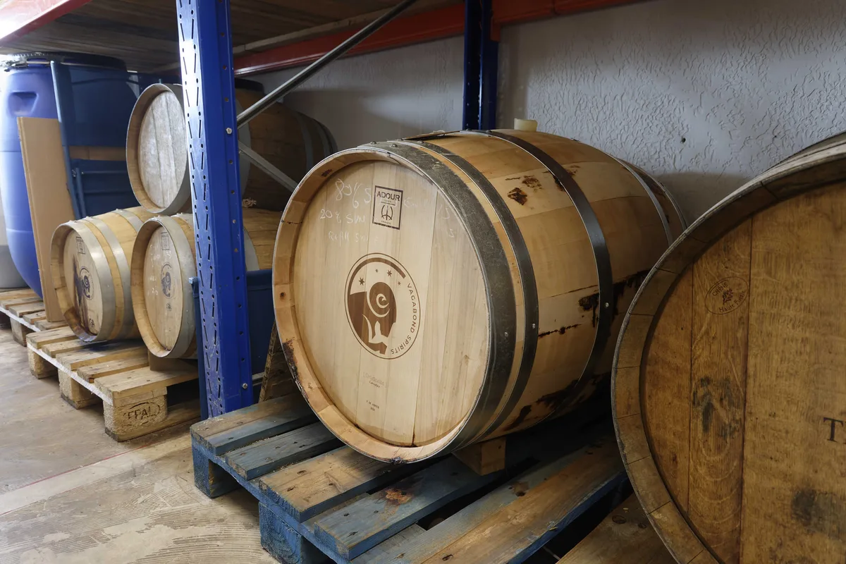 Casks on pallets in the Vagabond Spirits cellar, one of them branded with the house logo.