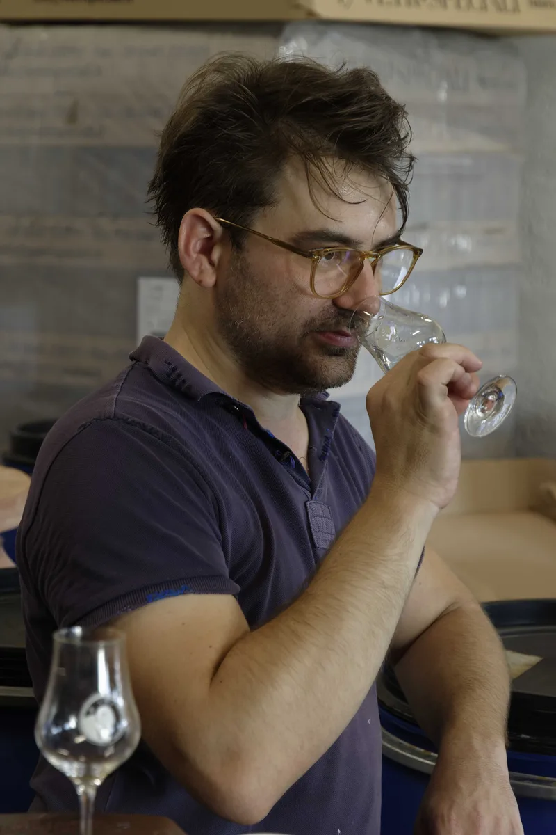Nicolas Petit nosing a rum sample from a tasting glass in his cellar.
