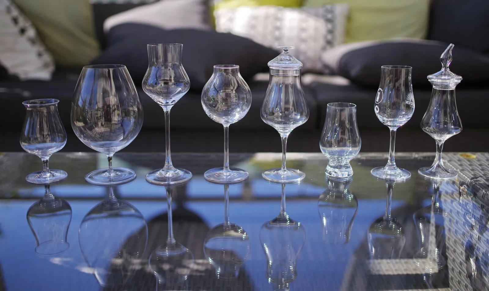 Eight tasting glasses of different shapes in a row on a glass table