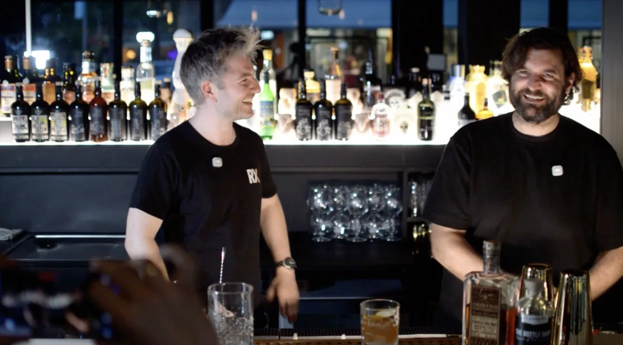 Oliver and Stefan Glück laughing behind the bar at Der Ludwig, a finished rum Old Fashioned with orange zest in front