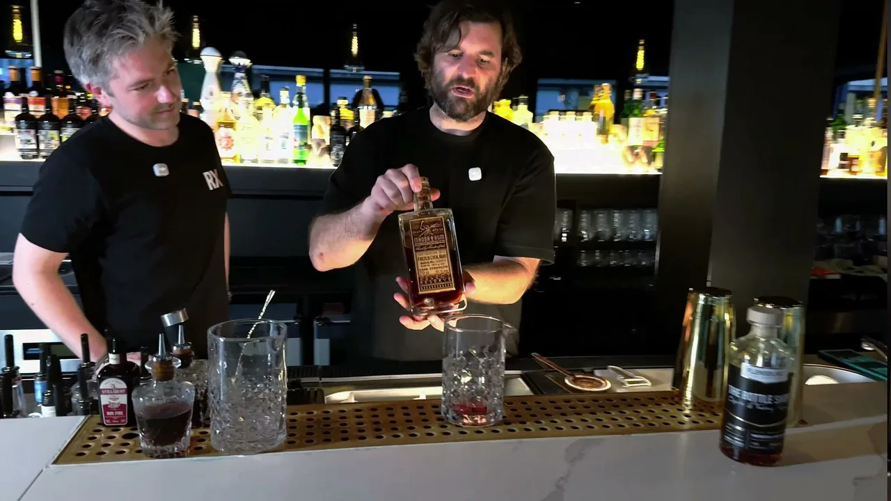 Stefan Glück presents the bottle of Mhoba Select Reserve French Cask, in front the mixing glass with muddled chili, next to Doc Fire bitters and the Bottle Shop bottle