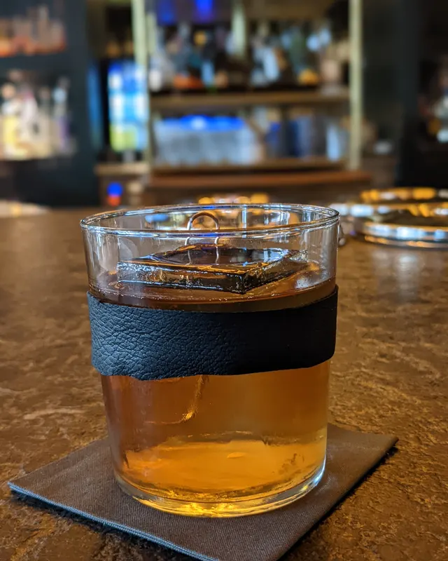 Old Fashioned in a glass with a leather sleeve on a black napkin
