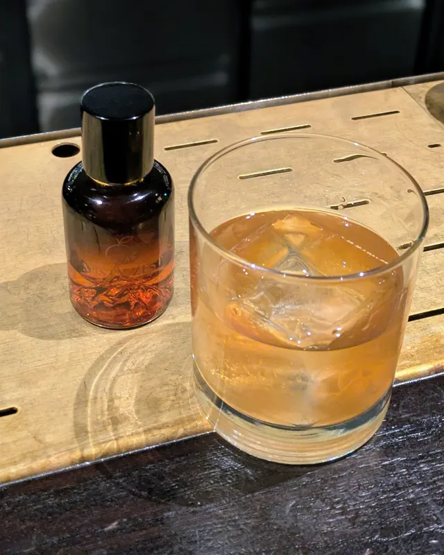Old Fashioned next to a small bitters bottle on a wooden tray